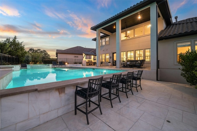 pool at dusk featuring a patio, an in ground hot tub, and ceiling fan