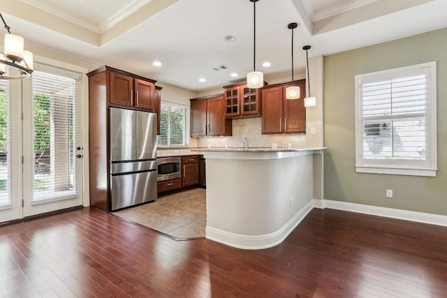 kitchen featuring pendant lighting, kitchen peninsula, dark wood-type flooring, and appliances with stainless steel finishes