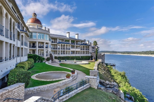 view of home's community featuring a lawn and a water view