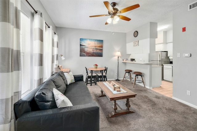 carpeted living room with a textured ceiling and ceiling fan