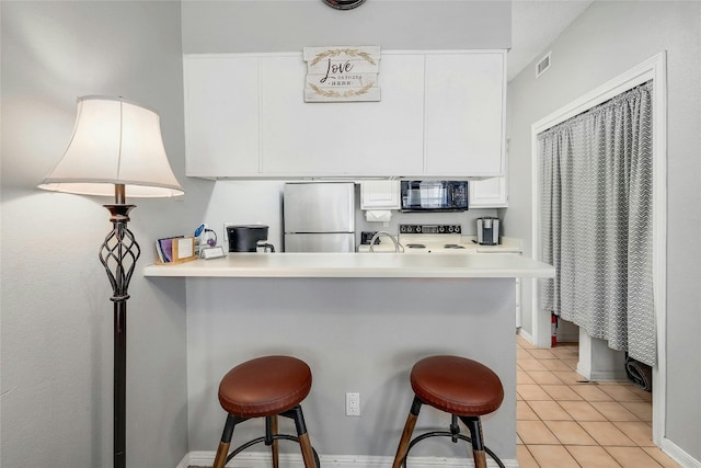 kitchen with a kitchen breakfast bar, stainless steel fridge, kitchen peninsula, and white cabinets