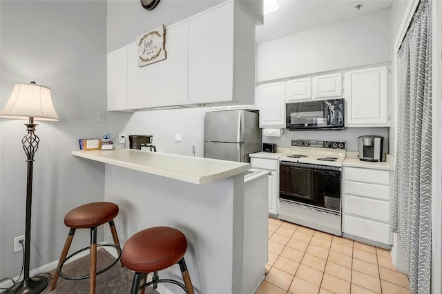 kitchen with a kitchen bar, electric stove, kitchen peninsula, and white cabinets