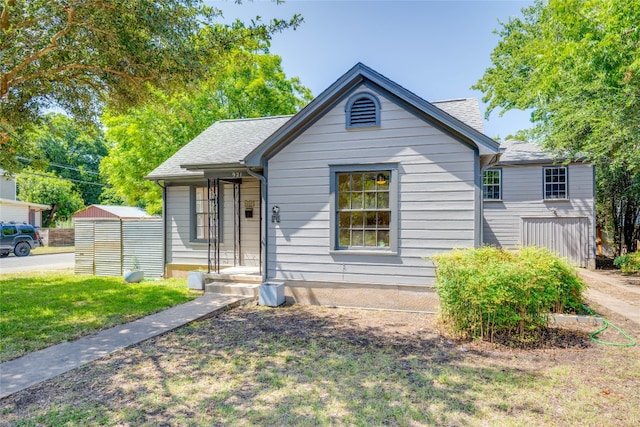 bungalow featuring a front lawn and a storage unit