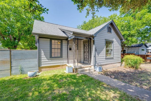 view of front of property with a front yard, fence, and roof with shingles