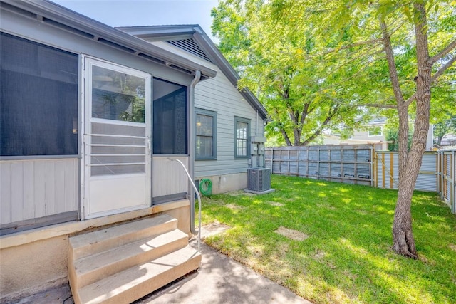 view of yard featuring entry steps, a fenced backyard, and central AC