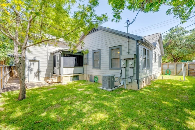 back of property featuring a yard, a fenced backyard, a sunroom, and central air condition unit