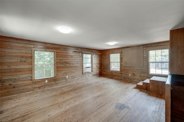 spare room with light wood finished floors and wooden walls