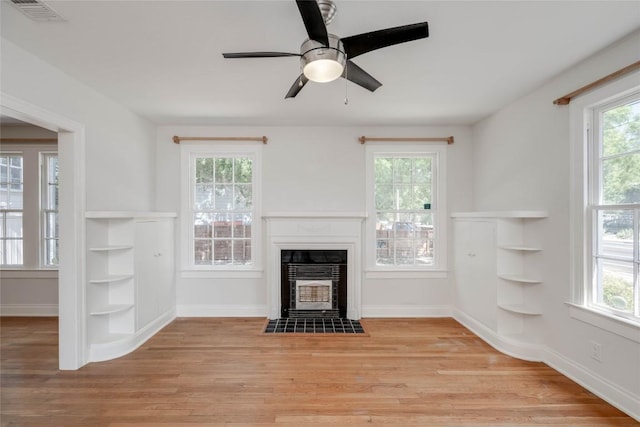 unfurnished living room featuring a fireplace with flush hearth, visible vents, light wood-style flooring, and a wealth of natural light