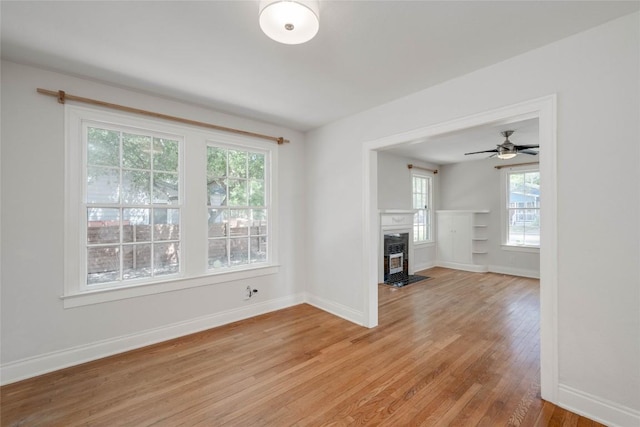 unfurnished living room with a fireplace with flush hearth, light wood-type flooring, and baseboards