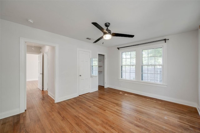 unfurnished bedroom with attic access, light wood-type flooring, ceiling fan, and baseboards