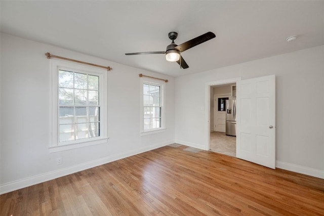 unfurnished room with light wood-type flooring, ceiling fan, and baseboards