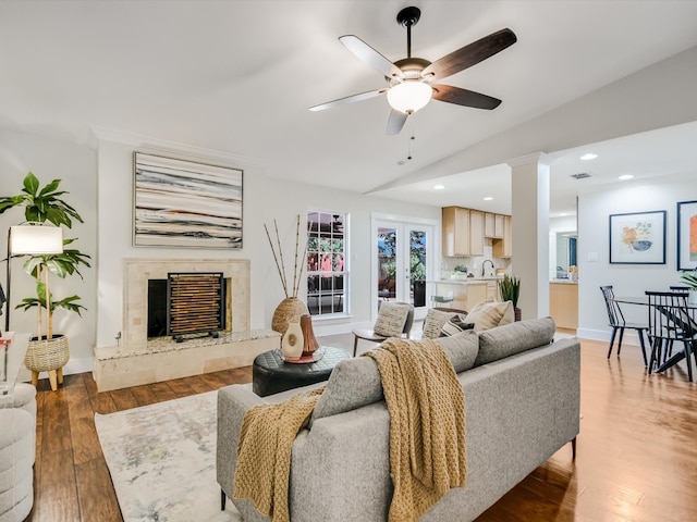 living room with vaulted ceiling, dark wood-type flooring, a high end fireplace, ceiling fan, and sink