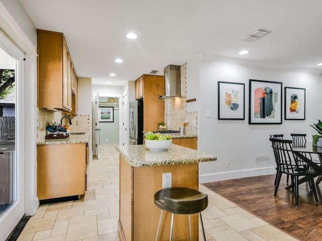 kitchen featuring light wood-type flooring, tasteful backsplash, sink, wall chimney range hood, and ornamental molding