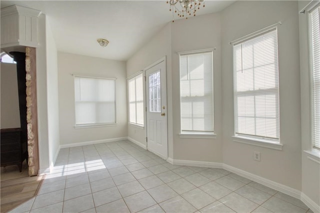 foyer entrance featuring light tile patterned flooring, a chandelier, and a healthy amount of sunlight