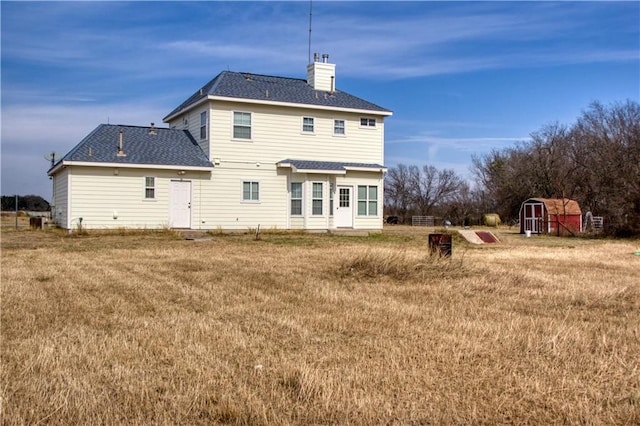 rear view of property featuring a shed and a yard