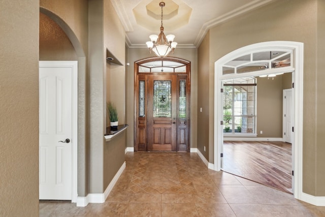 foyer with an inviting chandelier, ornamental molding, and light wood-type flooring