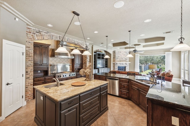 kitchen featuring an island with sink, hanging light fixtures, ornamental molding, sink, and stainless steel dishwasher