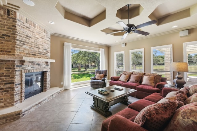 tiled living room with ceiling fan, a textured ceiling, a brick fireplace, ornamental molding, and coffered ceiling