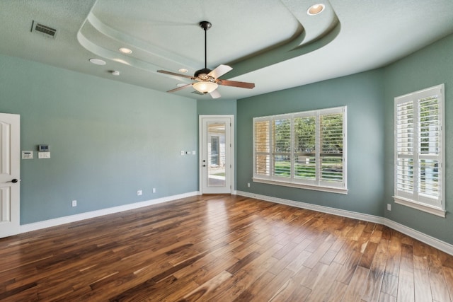 empty room featuring hardwood / wood-style floors, ceiling fan, and a raised ceiling