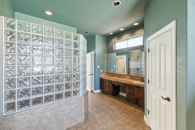 bathroom with vanity, tiled shower, and tile patterned flooring