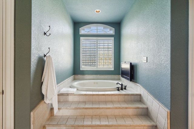 bathroom featuring a textured ceiling and tiled bath