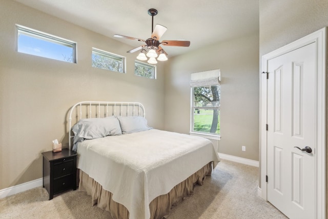 carpeted bedroom featuring multiple windows and ceiling fan