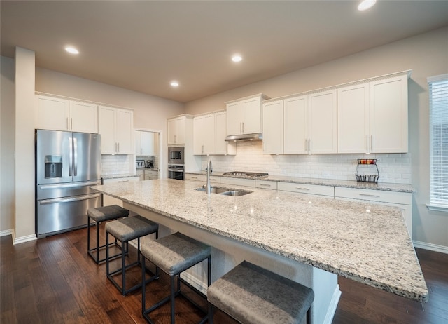 kitchen with sink, a center island with sink, white cabinetry, stainless steel appliances, and dark hardwood / wood-style floors