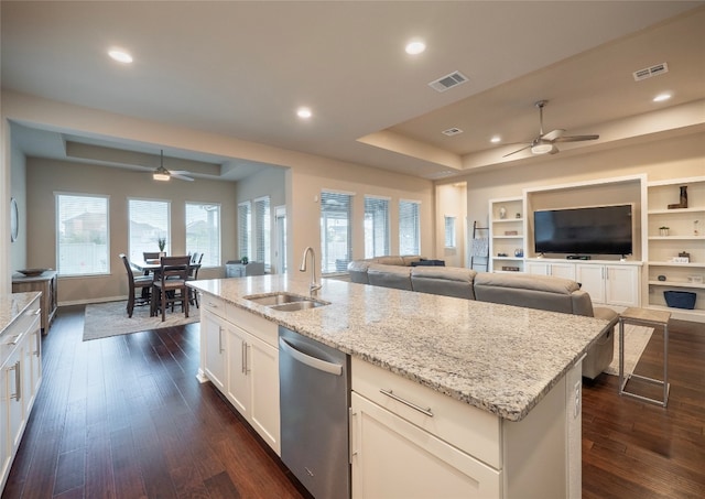 kitchen with dark wood-type flooring, light stone countertops, a center island with sink, stainless steel dishwasher, and sink