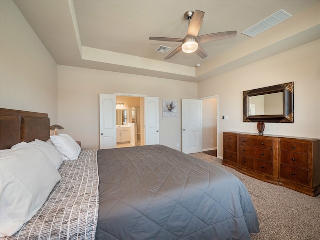 carpeted bedroom with connected bathroom, ceiling fan, and a raised ceiling