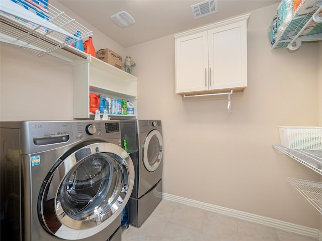 laundry room featuring washing machine and clothes dryer and cabinets