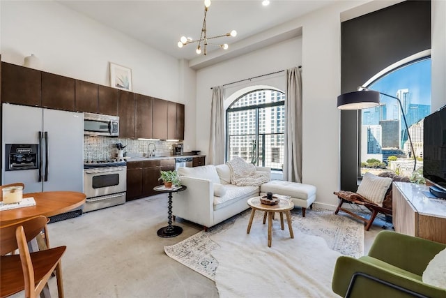 living room featuring a towering ceiling, sink, and a notable chandelier