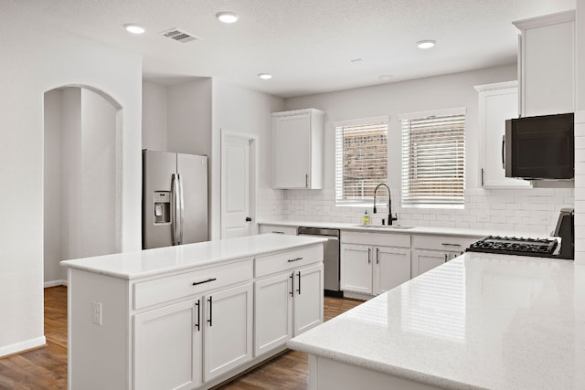 kitchen with white cabinets, sink, dark wood-type flooring, stainless steel appliances, and a center island