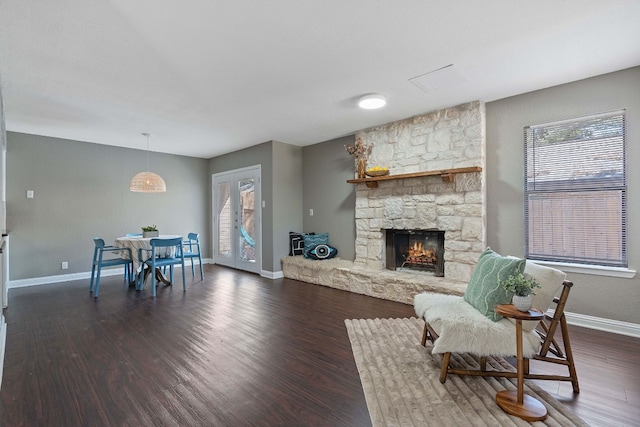 living room with dark hardwood / wood-style flooring and a stone fireplace