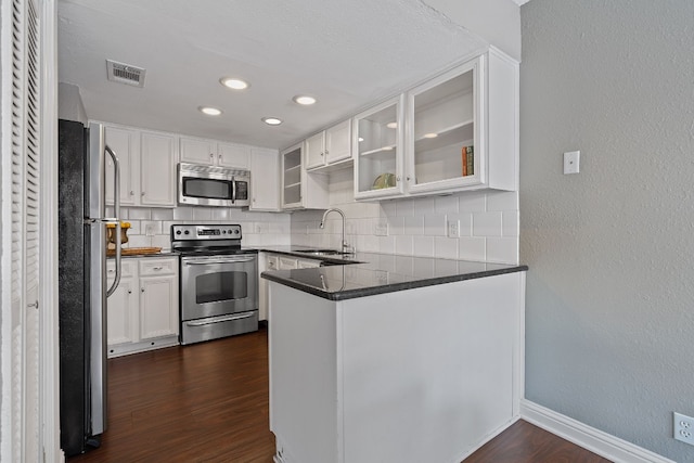 kitchen with white cabinets, sink, tasteful backsplash, kitchen peninsula, and stainless steel appliances