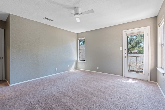 empty room featuring a textured ceiling, carpet floors, and ceiling fan