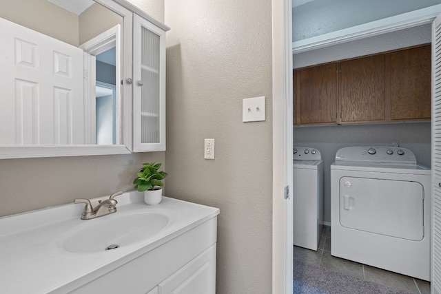 bathroom featuring washing machine and clothes dryer, tile patterned floors, and sink