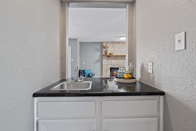 kitchen with a fireplace, white cabinetry, and sink