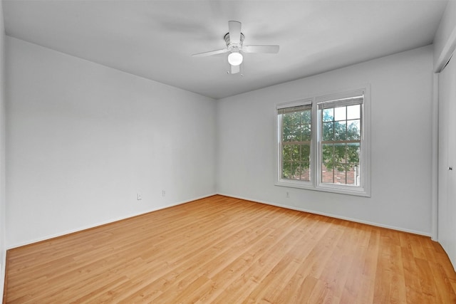 empty room with light wood-type flooring, a ceiling fan, and baseboards