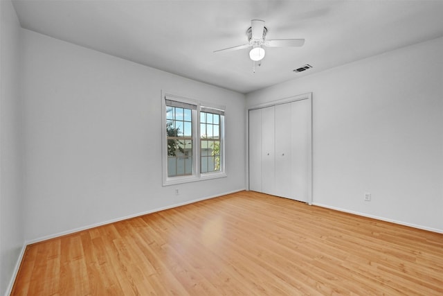 unfurnished bedroom featuring a closet, visible vents, a ceiling fan, wood finished floors, and baseboards