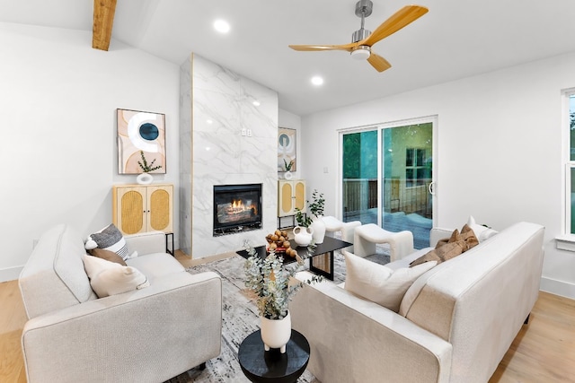 living room featuring light hardwood / wood-style flooring, a fireplace, lofted ceiling with beams, and ceiling fan