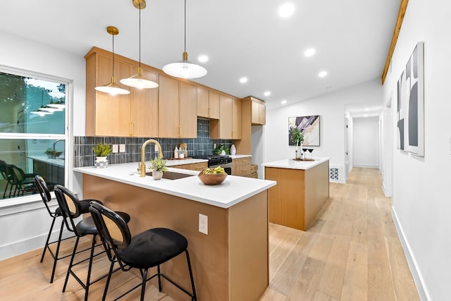 kitchen featuring kitchen peninsula, decorative backsplash, gas range, light hardwood / wood-style floors, and decorative light fixtures