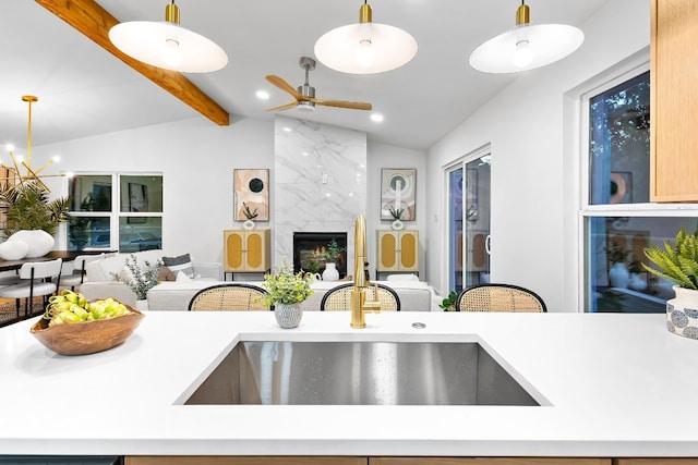 kitchen featuring lofted ceiling with beams, a fireplace, and hanging light fixtures