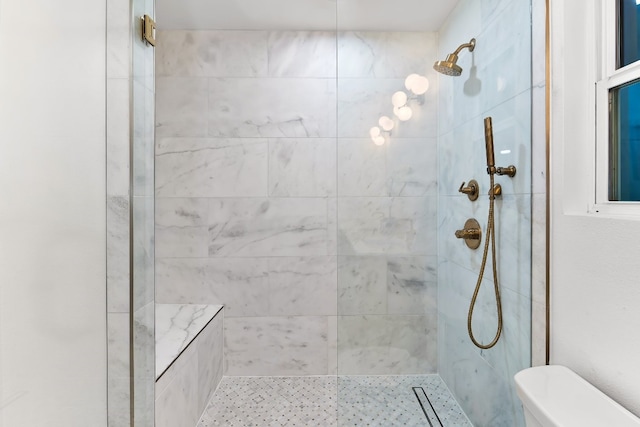 bathroom featuring a tile shower and toilet