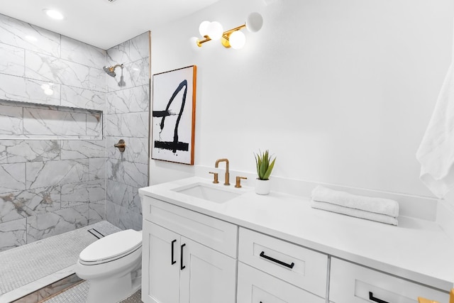 bathroom featuring toilet, vanity, and tiled shower