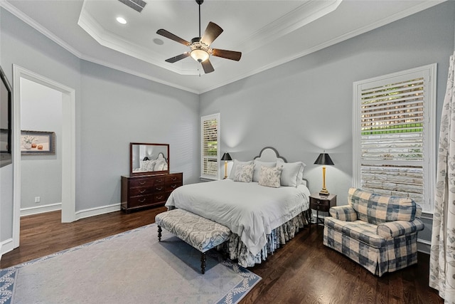 bedroom with baseboards, a tray ceiling, dark wood-type flooring, and crown molding