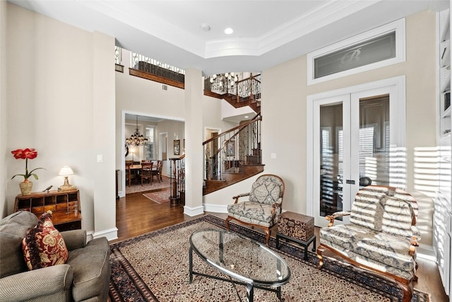 living room featuring french doors, a raised ceiling, ornamental molding, wood finished floors, and stairs