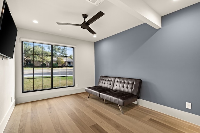 sitting room featuring beam ceiling, light hardwood / wood-style floors, and ceiling fan