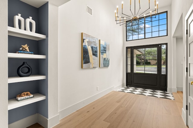 entrance foyer featuring wood-type flooring, a high ceiling, and a chandelier