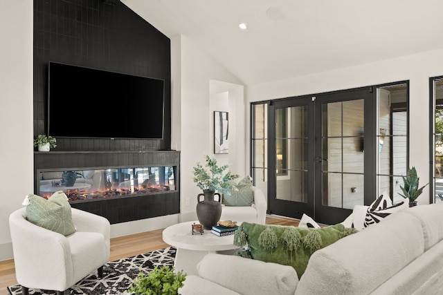 living room with a fireplace, hardwood / wood-style floors, french doors, and lofted ceiling