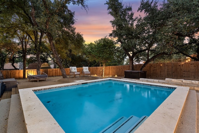 pool at dusk featuring a patio, a trampoline, and a hot tub